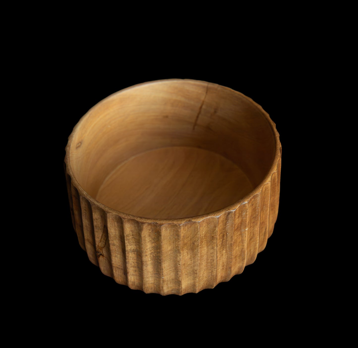 Wooden bowl with ribbed texture on a black background