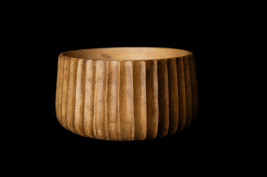 Wooden bowl with a ribbed texture on a black background